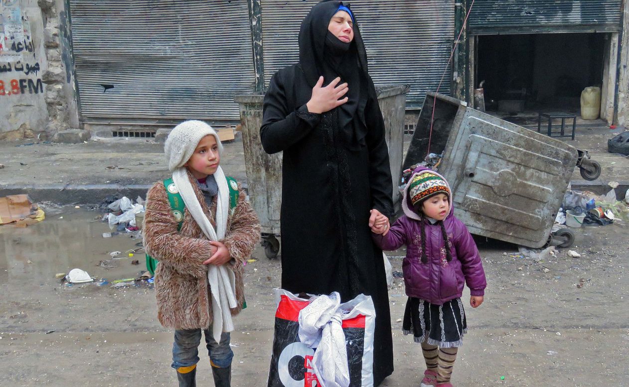 A woman reacts as she evacuates the Bustan al-Qasr neighborhood with her two children on December 13.