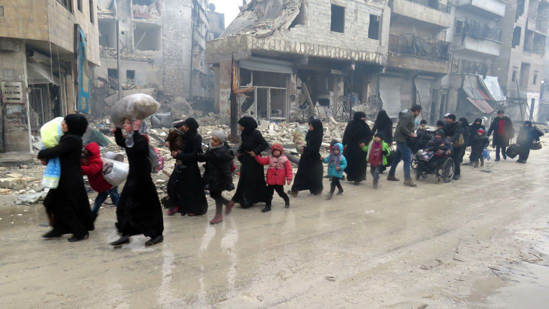 Syrian residents, fleeing violence in the Bustan al-Qasr neighborhood, arrive in Aleppo's Fardos neighborhood on December 13.