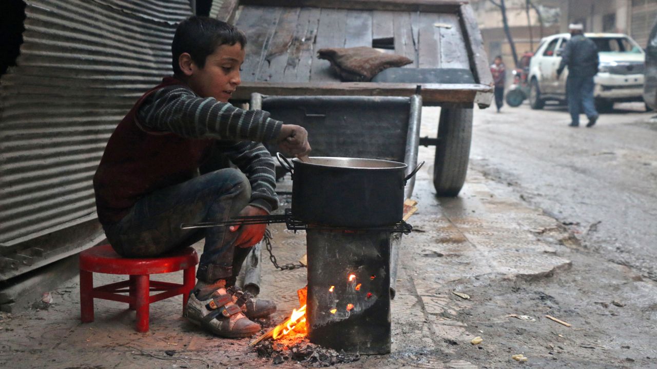 A Syrian child cooks in the street in a rebel-held area of Aleppo on December 13.