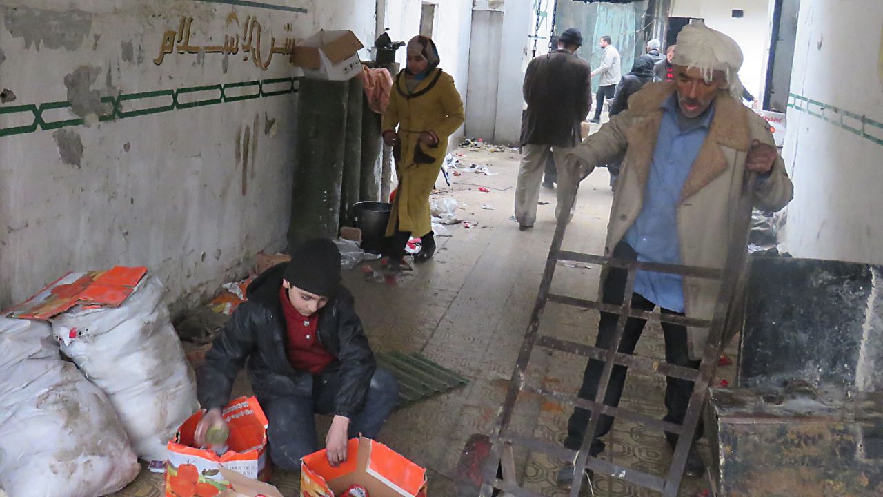 Syrian civilians take food from a storage room that was formerly held by the opposition forces in eastern Aleppo's al-Kalasseh neighborhood on December 13.