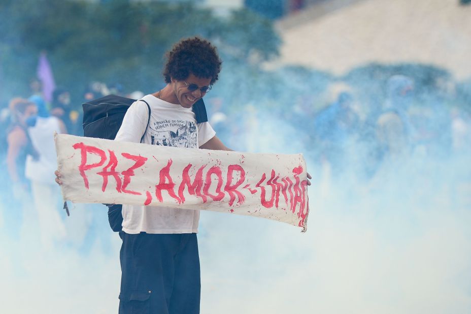 A demonstrator holds a sign that reads, "peace, love, and unity," in the midst of a clash between protesters and police outside the National Congress in Brasilia on December 13.