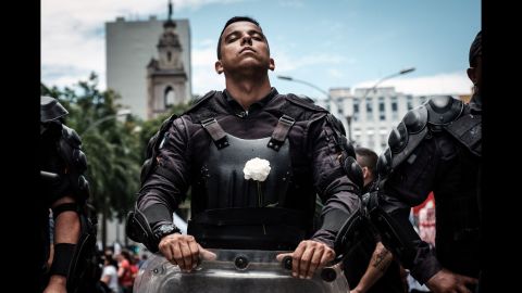 A police officer wears a white flower on his bulletproof vest while participating in a public servants' protest against the austerity measures in front of the State Assembly in Rio de Janeiro on Monday, December 12, as lawmakers began the voting measures.