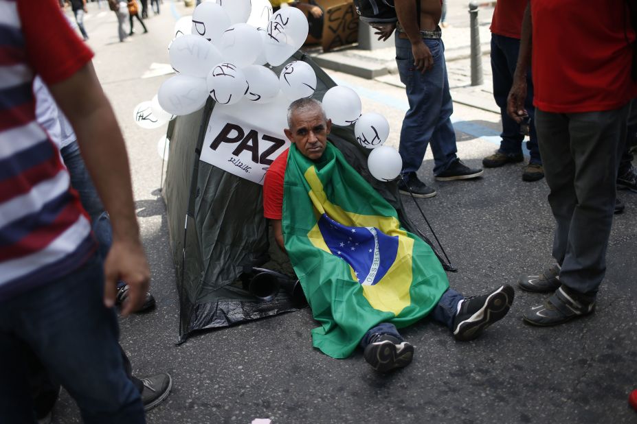 A demonstrator sits wrapped in a Brazilian flag outside the state legislature in Rio de Janeiro on December 13, where police, firefighters, and teachers gathered for the rally.
