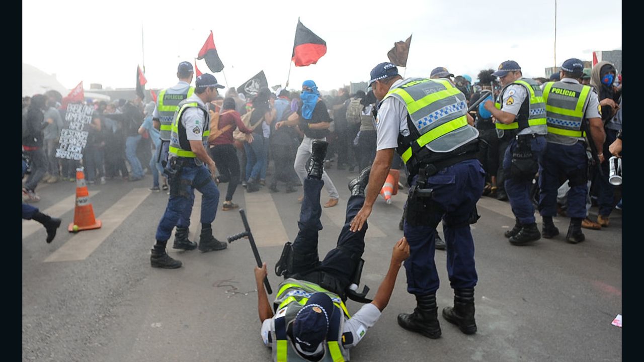 A police officer is knocked down during clashes with demonstrators protesting in front of the National Congress in Brasilia on December 13, 2016.
