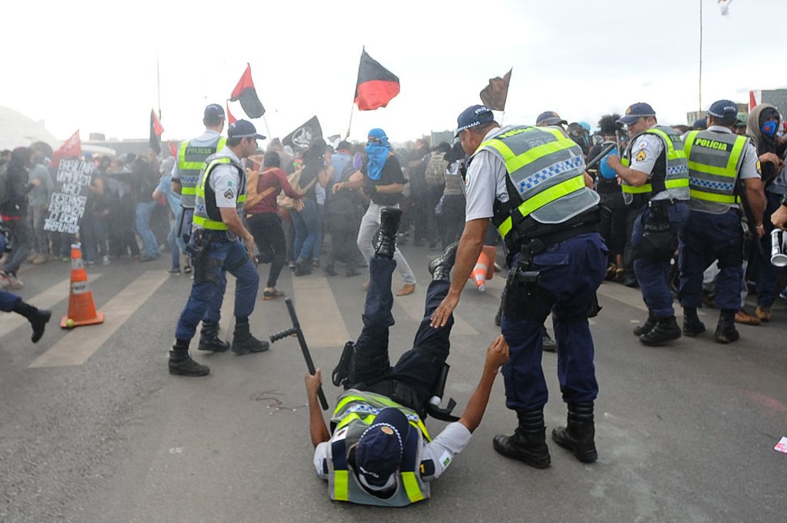 A police officer is knocked down during clashes with demonstrators protesting in front of the National Congress in Brasilia on December 13, 2016. 