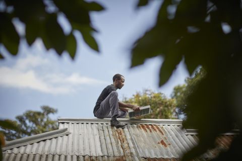 A service officer installs a panel on a new customer's rooftop in Arusha, Tanzania.