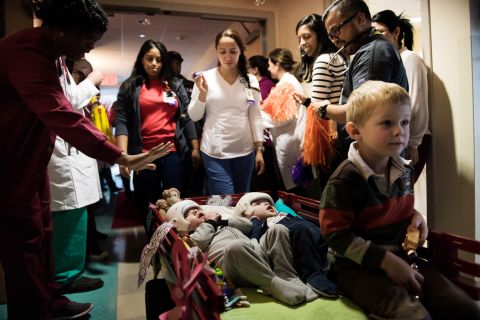 Jadon, left, and Anias McDonald look up at hospital staff as they leave their room at Montefiore Children's Hospital in New York. Their older brother, Aza, proudly sits at the front of the wagon. It was mid-December and they were headed to rehab.