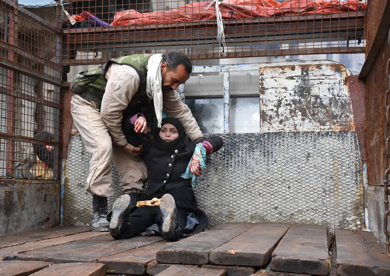 A wounded woman is helped into the bed of a truck on December 14.