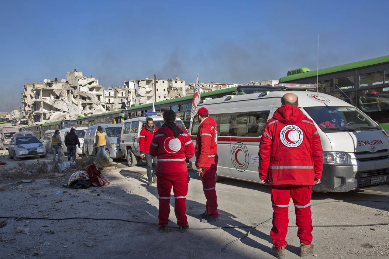 Staff members of the Syrian Red Crescent wait near ambulances as the evacuation operation gets underway on December 15.