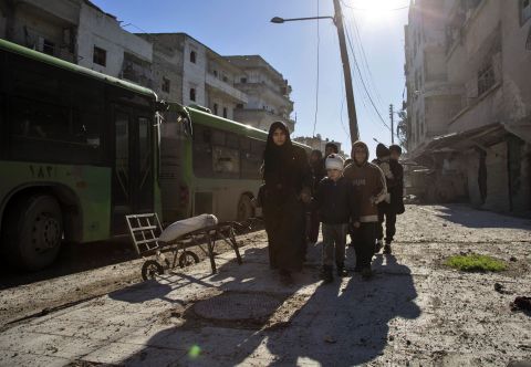 A woman leads family members toward the evacuation buses on December 15.
