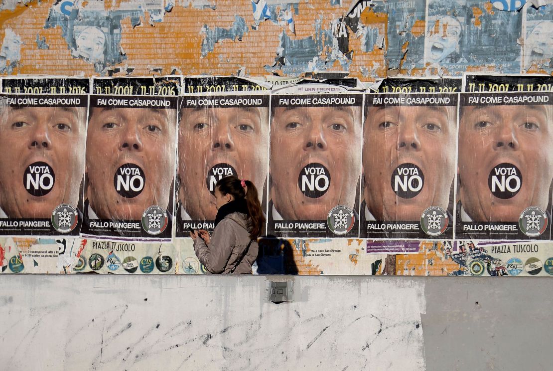 A woman walks past posters for the far-right CasaPound party, urging a "No" vote in Italy's referendum.