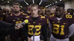 University of Minnesota wide receiver Drew Wolitarsky, flanked by quarterback Mitch Leidner, left, and tight end Duke Anyanwu stands in front of other team members as he reads a statement on behalf of the players in the Nagurski Football Complex in Minneapolis, Minn., Thursday night, Dec. 15, 2016.  The players delivered a defiant rebuke of the university's decision to suspend 10 of their teammates, saying they would not participate in any football activities until the school president and athletic director apologized and revoked the suspensions. If that meant they don't play in the upcoming Holiday Bowl against Washington State, they appeared poised to stand firm. (Jeff Wheeler/Star Tribune via AP)