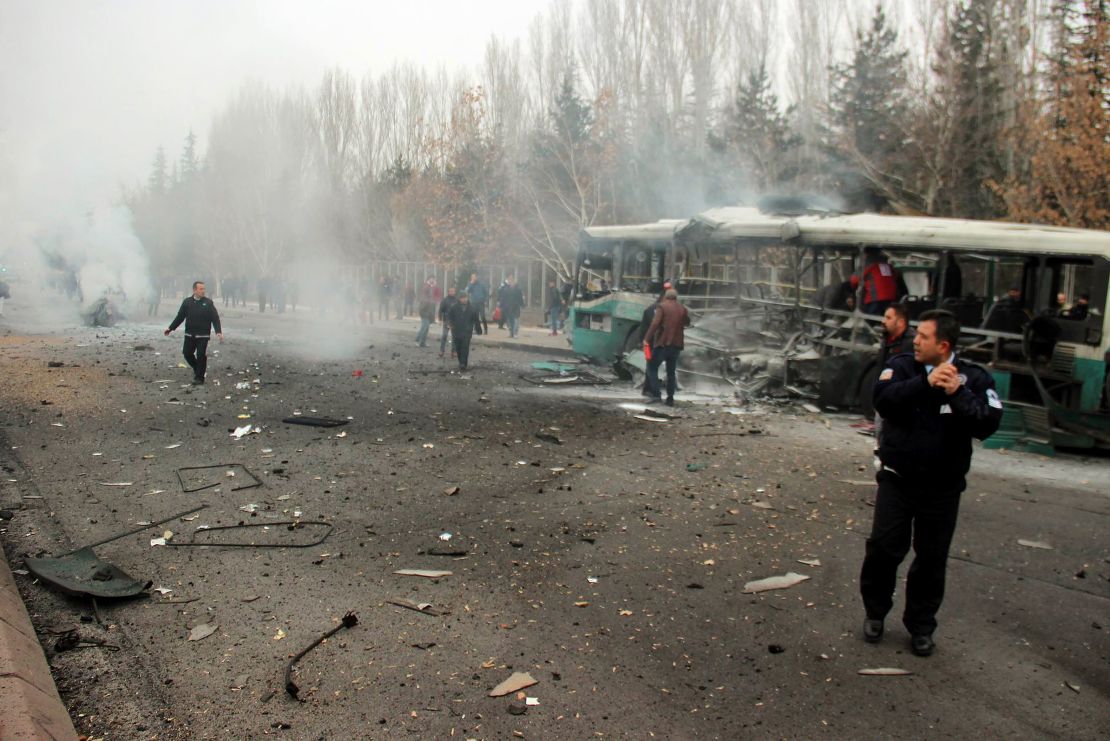 A police officer and people walking next to the wreck of public bus following an explosion on December 17, 2016 in Kayseri, central Turkey.