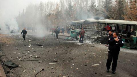 A police officer and people walking next to the wreck of public bus following an explosion on December 17, 2016 in Kayseri, central Turkey.