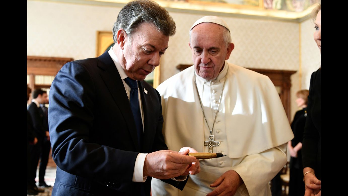 Colombian President Juan Manuel Santos, left, reads aloud words engraved on a pen as he meets with Pope Francis at the Vatican, Friday, December 16, 2016. The words "The bullets have written our past, education will write our future" are engraved on the pen, made from a recycled bullet once used in the civil war between the Colombian government and the Revolutionary Armed Forces of Colombia (FARC). The pen was later used to sign the peace agreements between the parties earlier this year. Santos, who was awarded the 2016 Nobel Peace Prize for his efforts to end the region's longest-running conflict, presented Pope Francis with the pen.