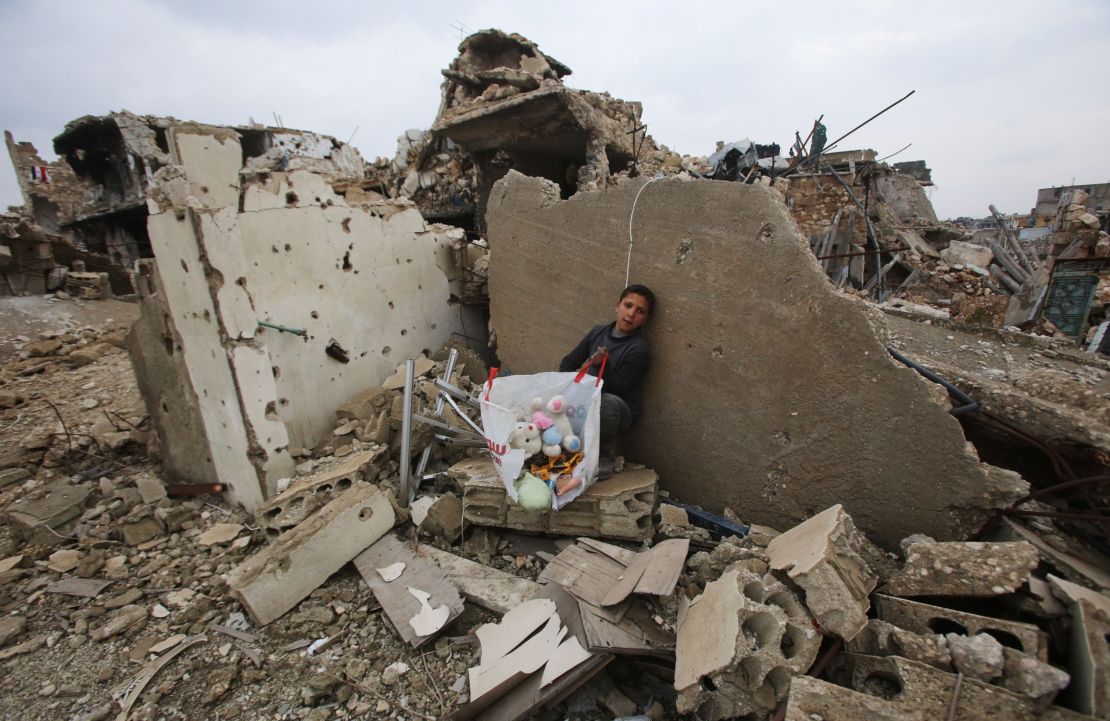 A Syrian boy with his belongings in the rubble of his home in Aleppo's Al-Arkoub neighborhood on Saturday.