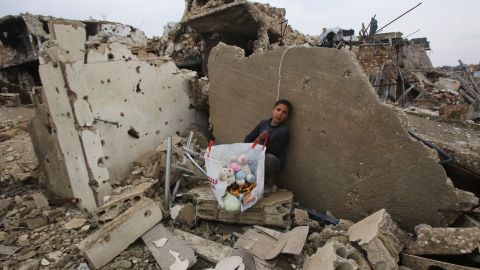 A boy sits with his belongings where his house once stood in Aleppo on December 17, 2016.
