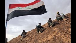 TOPSHOT - Shiite fighters from the Hashed al-Shaabi (Popular Mobilisation) paramilitary units sits under an Iraqi flag as they advance towards the village of Shwah, south of the city of Tal Afar on the western outskirts of Mosul, on December 13, 2016, during an ongoing operation against Islamic State (IS) group jihadists.Hashed al-Shaabi paramilitary forces said they retook three more villages southwest of Mosul, completing another phase in operations aimed at cutting the jihadists' link to Syria. / AFP / AHMAD AL-RUBAYE        (Photo credit should read AHMAD AL-RUBAYE/AFP/Getty Images)
