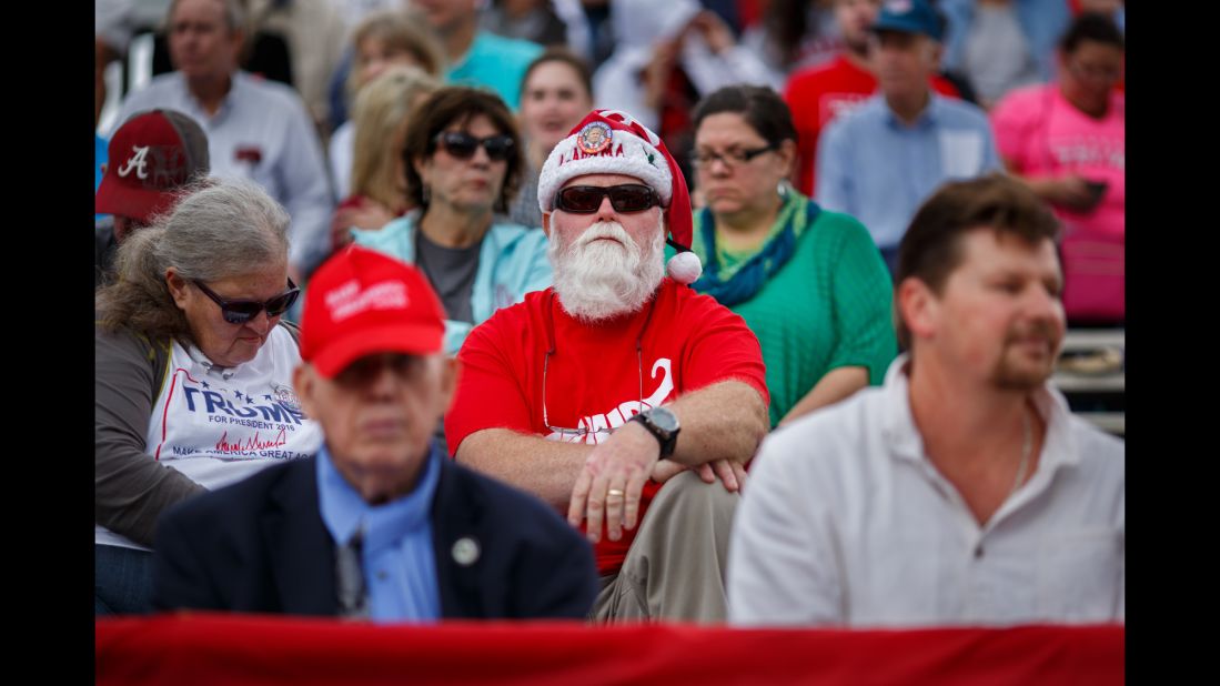 David Docter of Foley, Alabama, sits in the stands wearing a Santa hat and a Trump shirt.