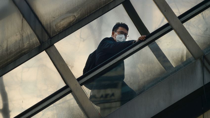 A man wearing a mask rides an escalator to cross an overpass in Beijing on December 19, 2016.
Hospital visits spiked, roads were closed and flights cancelled on December 19 as China choked under a vast cloud of toxic smog, with forecasters warning the worse was yet to come.