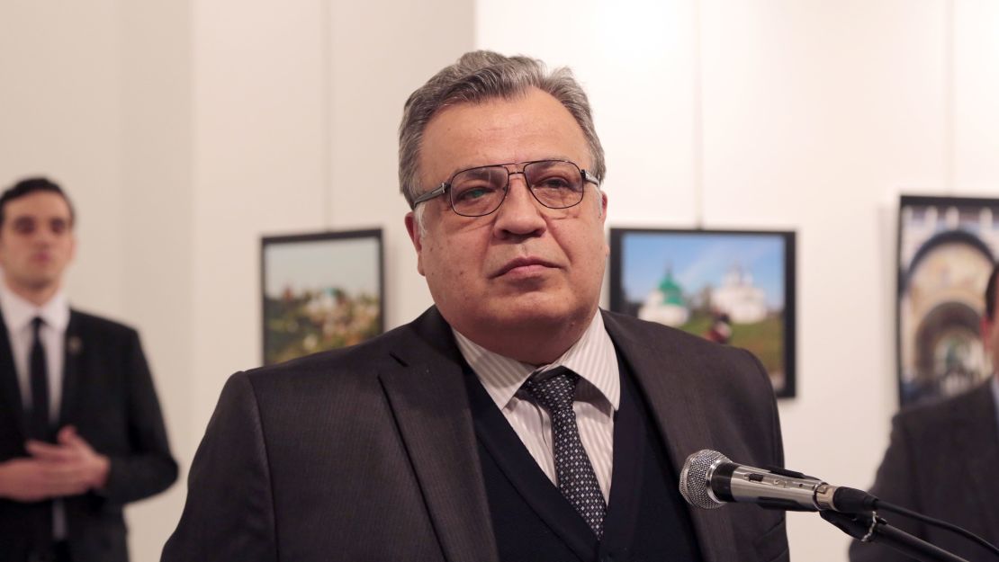 Karlov moments before he was gunned down while speaking at a new photo exhibition in Ankara, Turkey. The gunman is seen at rear on the left. 