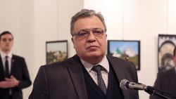 The Russian Ambassador to Turkey Andrei Karlov speaks a gallery in Ankara Monday Dec. 19, 2016. A gunman opened fire on Russia's ambassador to Turkey Karlov at a photo exhibition on Monday. The Russian foreign ministry spokeswoman said he was hospitalized with a gunshot wound. The gunman is seen at rear on the left.  (AP Photo/Burhan Ozbilici)
