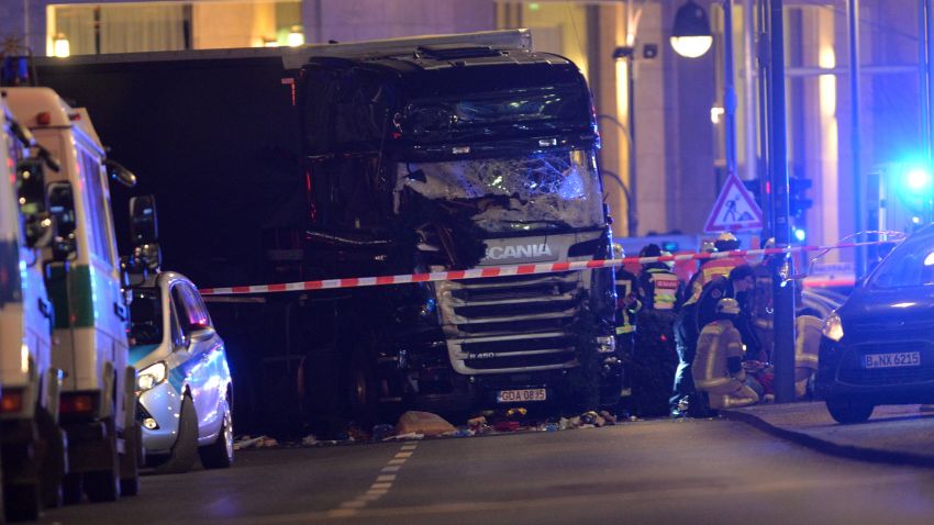 epa05682696 Rescue workers at the scenes and the truck that crashed into a Christmas market, close to the Kaiser Wilhelm memorial church in Berlin, Germany, 19 December 2016. According to the police, at least one man is reported killed in what police suspect it was a deliberate attack.  EPA/PAUL ZINKEN