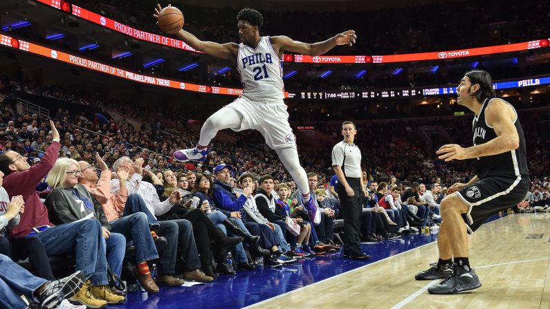 Joel Embiid, a center for the NBA's Philadelphia 76ers, dives into the crowd to keep a ball in play against Brooklyn on Sunday, December 18.