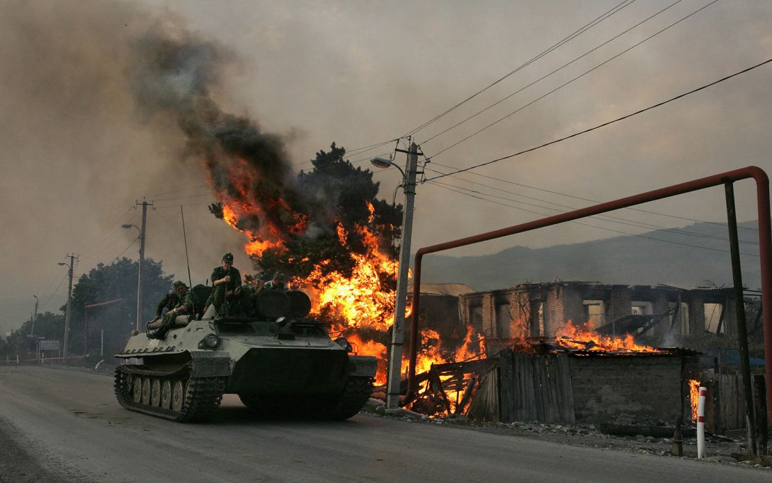 A Russian armoured vehicle passes a house set on fire by seperatist militia during the conflict between Georgia and Russia, on August 18, 2008.