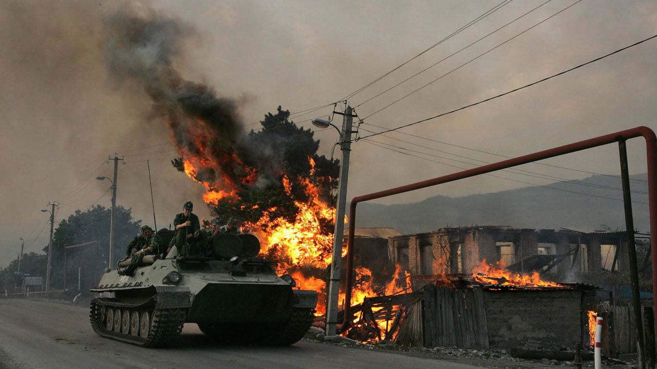 A Russian armoured vehicle passes a house set on fire by seperatist militia during the conflict between  Georgia and Russia, on August 18, 2008.