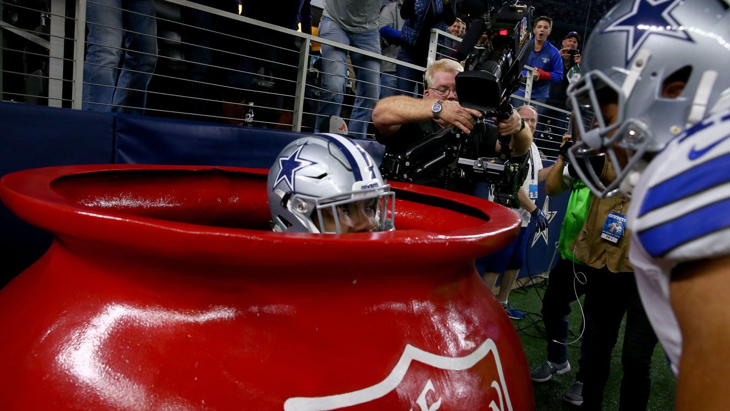 The Dallas Cowboys' Ezekiel Elliott celebrates in a Salvation Army kettle after scoring a touchdown Sunday.