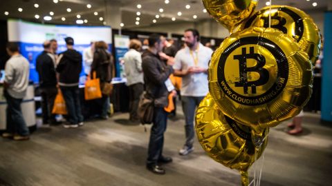 Its value fluctuates and is not regulated, although payment companies that trade with Bitcoin tend to fall under the same regulations as conventional money transfer services. Pictured: People attend a Bitcoin conference in New York in 2014. <br />