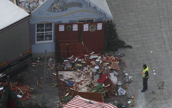 A rescue worker looks at destroyed market stalls near the truck's trailer.