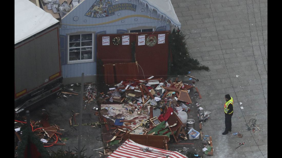 A rescue worker looks at destroyed market stalls near the truck's trailer.