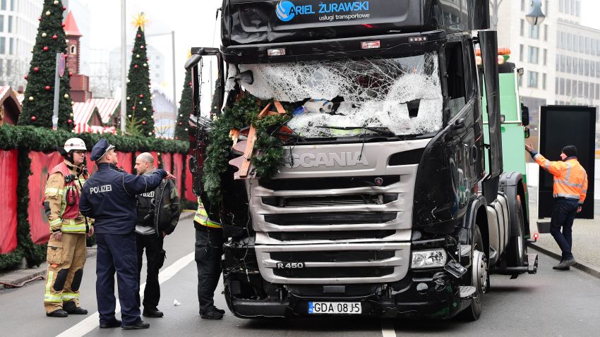 A policeman and firemen stand next to a truck on December 20, 2016 at the scene where it crashed into a Christmas market near the Kaiser-Wilhelm-Gedaechtniskirche (Kaiser Wilhelm Memorial Church) in Berlin.
German police said they were treating as "a probable terrorist attack" the killing of 12 people when the speeding lorry cut a bloody swath through the packed Berlin Christmas market.