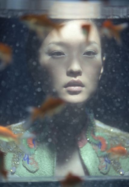 Supermodel Du Juan stares through a softly lit fish tank, lost in a pastel-colored soliloquy.