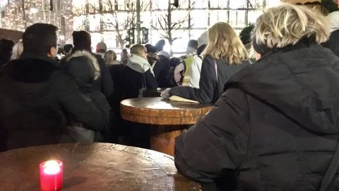 Mourners gather around tables at the closed Christmas market to listen to the service inside the Memorial Church.