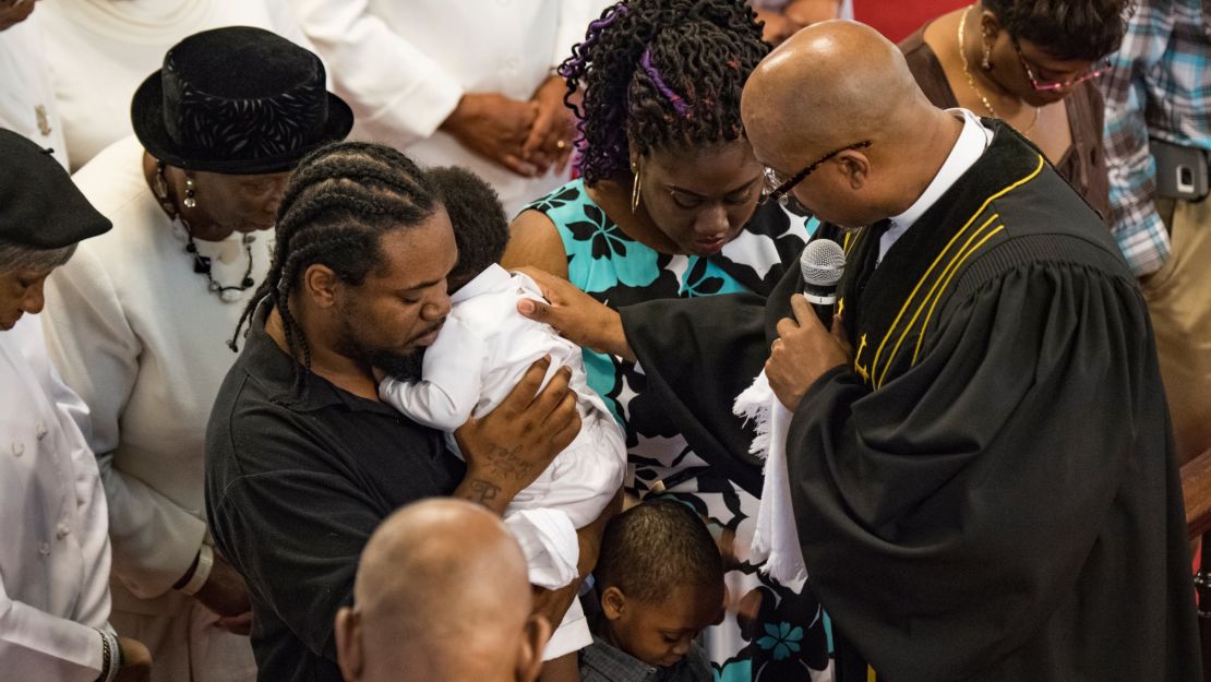 The Rev. Eric S.C. Manning of Emanuel African Methodist Episcopal Church prays with Anthony and Jatterah Wright as they baptize their 1-year-old son Kaiden Tysean Isaiah last month.