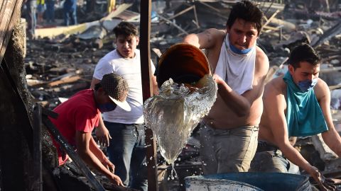 People work to extinguish embers still burning in the debris from the explosion.