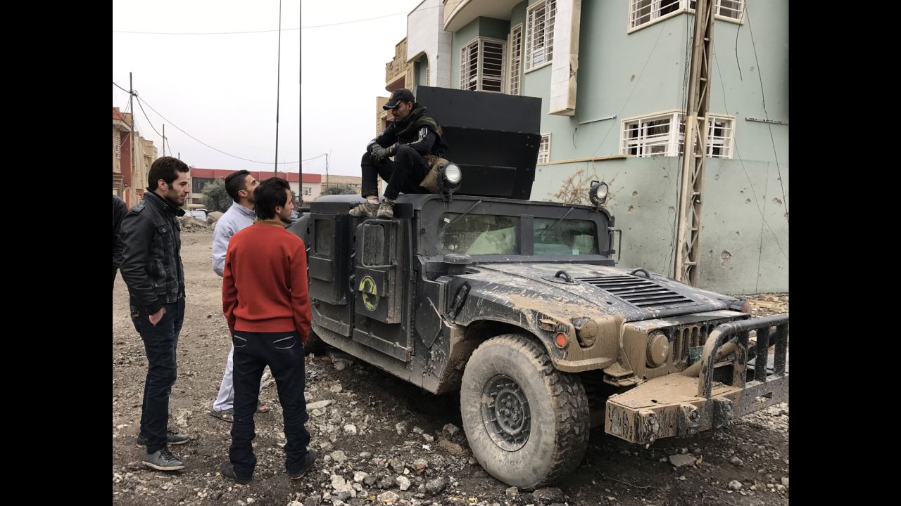 Civilians from Al-Barid neighborhood in eastern Mosul chat with a counterterrorism force member sitting on a CTF Humvee.