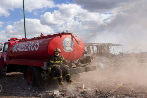 A firefighter rests on the back of a truck.