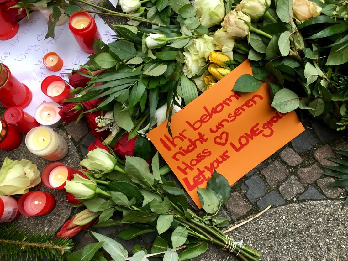 People leave tributes to the Berlin victims. One note reads, "Let your love grow."