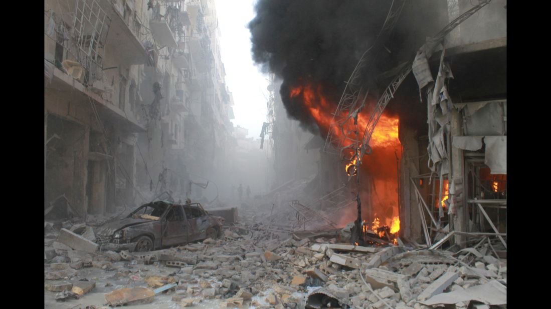 Debris covers a street and flames rise from a building after a reported airstrike by Syrian government forces on March 7, 2014, during the Friday prayer in the Sukkari neighborhood of  Aleppo.