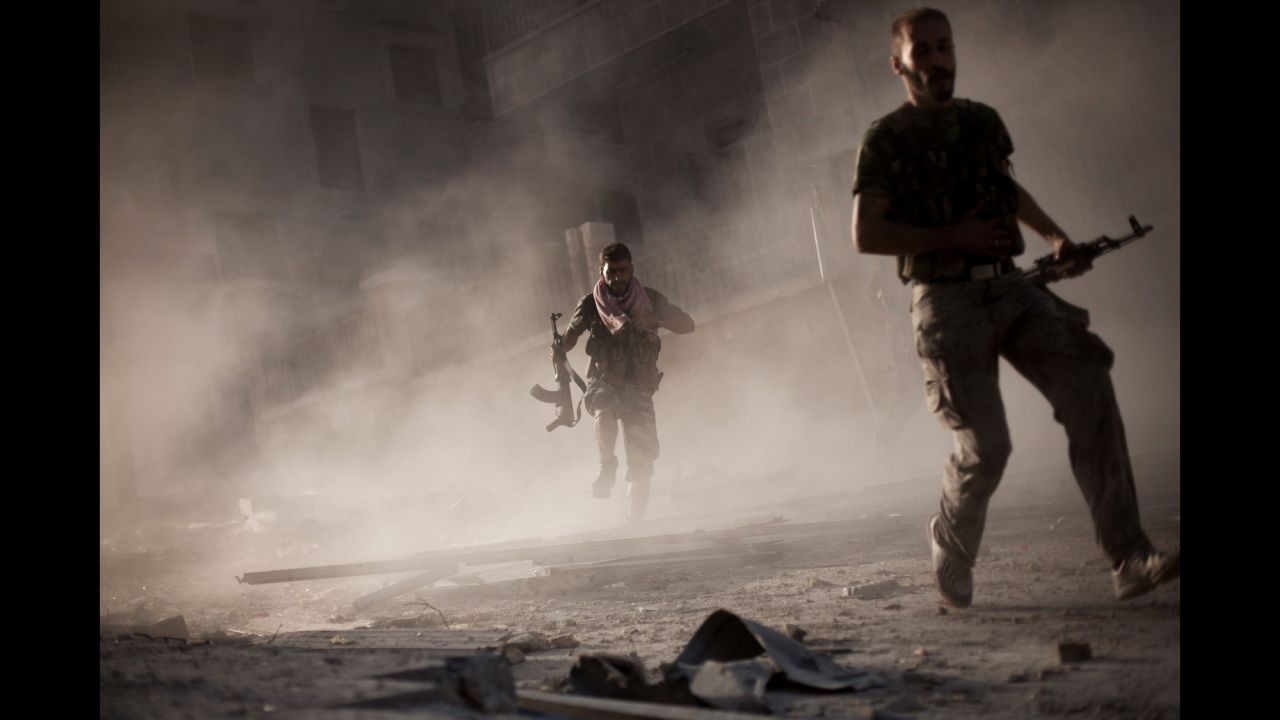 On September 7, 2012, Free Syrian Army fighters run after attacking a Syrian army tank during fighting in the Izaa district of Aleppo.
