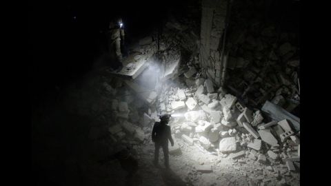 Search and rescue team members inspect collapsed buildings after Assad regime forces attacked residential areas in the Karm al-Beik region of Aleppo on July 9, 2015.