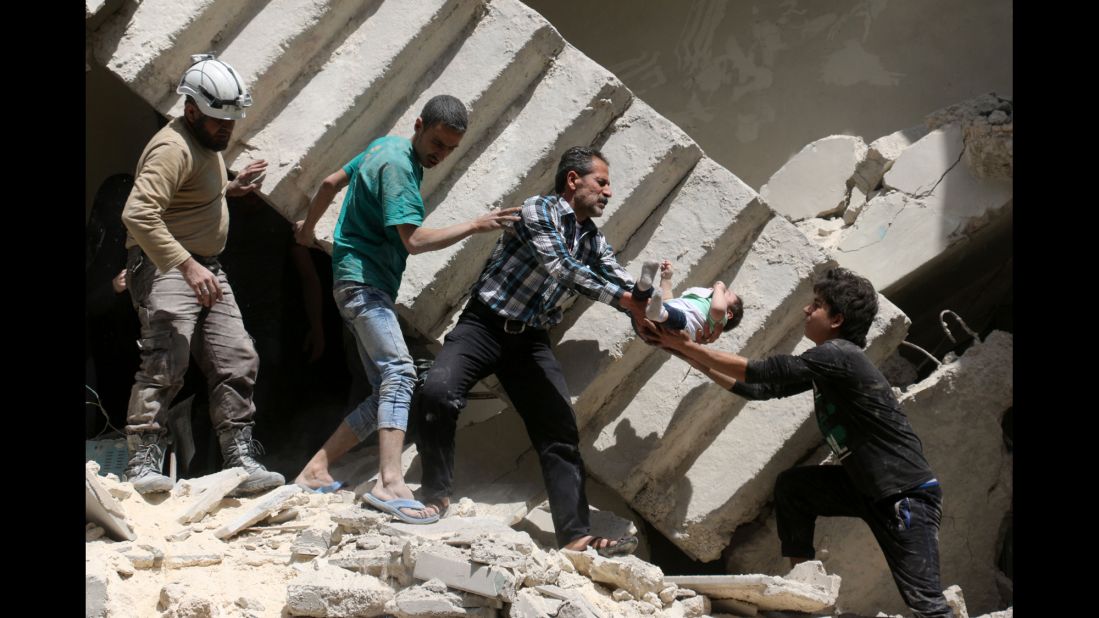 Syrian civil defense volunteers and rescuers remove a baby from under the rubble of a destroyed building after a reported airstrike on the rebel-held neighborhood of al-Kalasa in Aleppo on April 28, 2016.