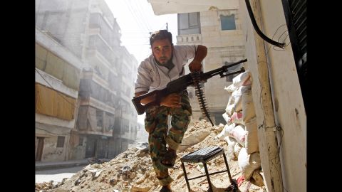 A Free Syrian Army fighter takes cover during clashes with Syrian army soldiers in the Salaheddine neighborhood of central Aleppo on August 7, 2012.