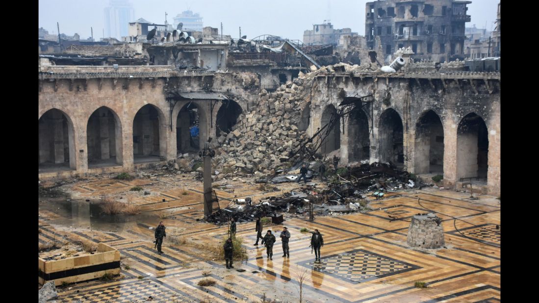 Syrian pro-government forces walk in the damaged ancient Umayyad Mosque in the old city of Aleppo on December 13, 2016, after they captured the area.