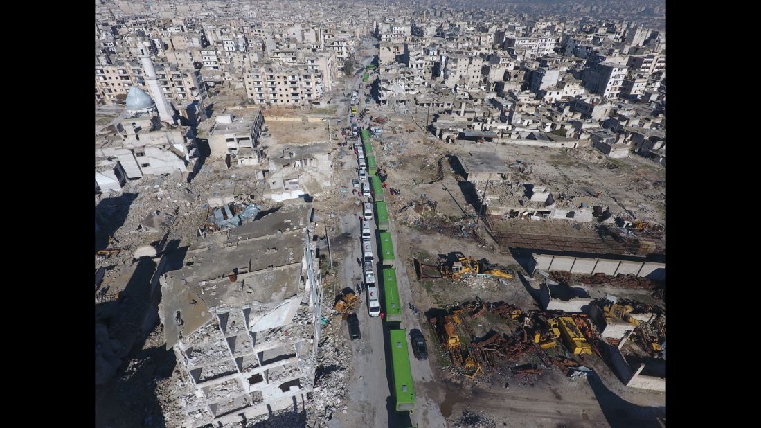An aerial view shows a convoy of buses and ambulances waiting at a crossing point in the Amiriyah district of Aleppo on December 15, 2016, to evacuate civilians trying to flee from areas under siege by Iran-led Shiite militias and Assad regime forces.