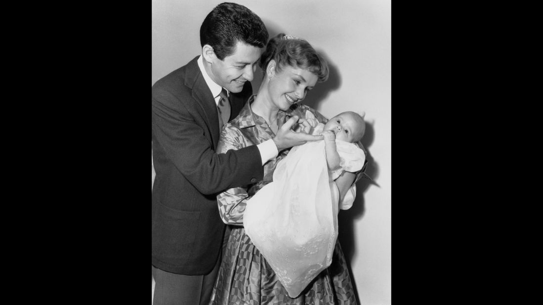Fisher was born in Beverly Hills on October 21, 1956, to Eddie Fisher and Debbie Reynolds. Here, they gaze proudly at their newborn daughter on January 2, 1957.